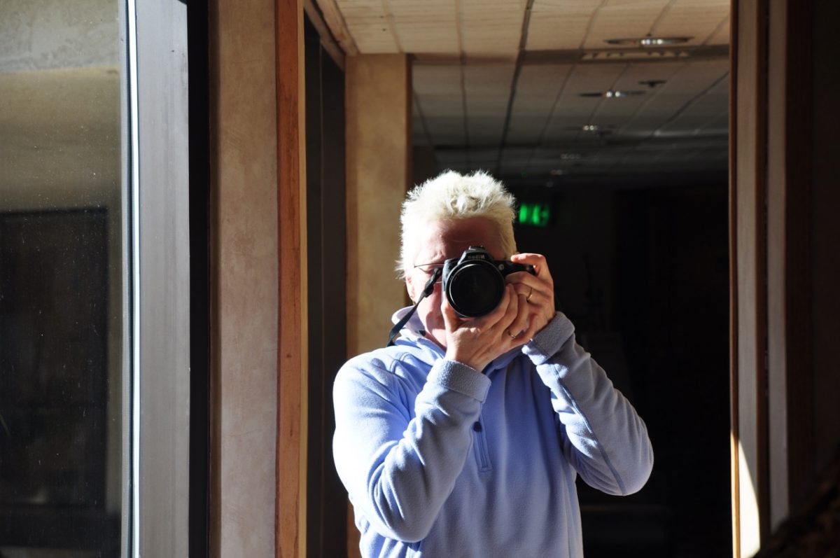 Woman with a camera taking a picture of herself in a mirror.