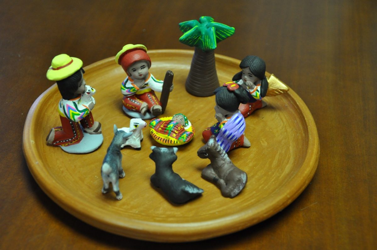 A miniature Latin American nativity set on a small wooden plate.