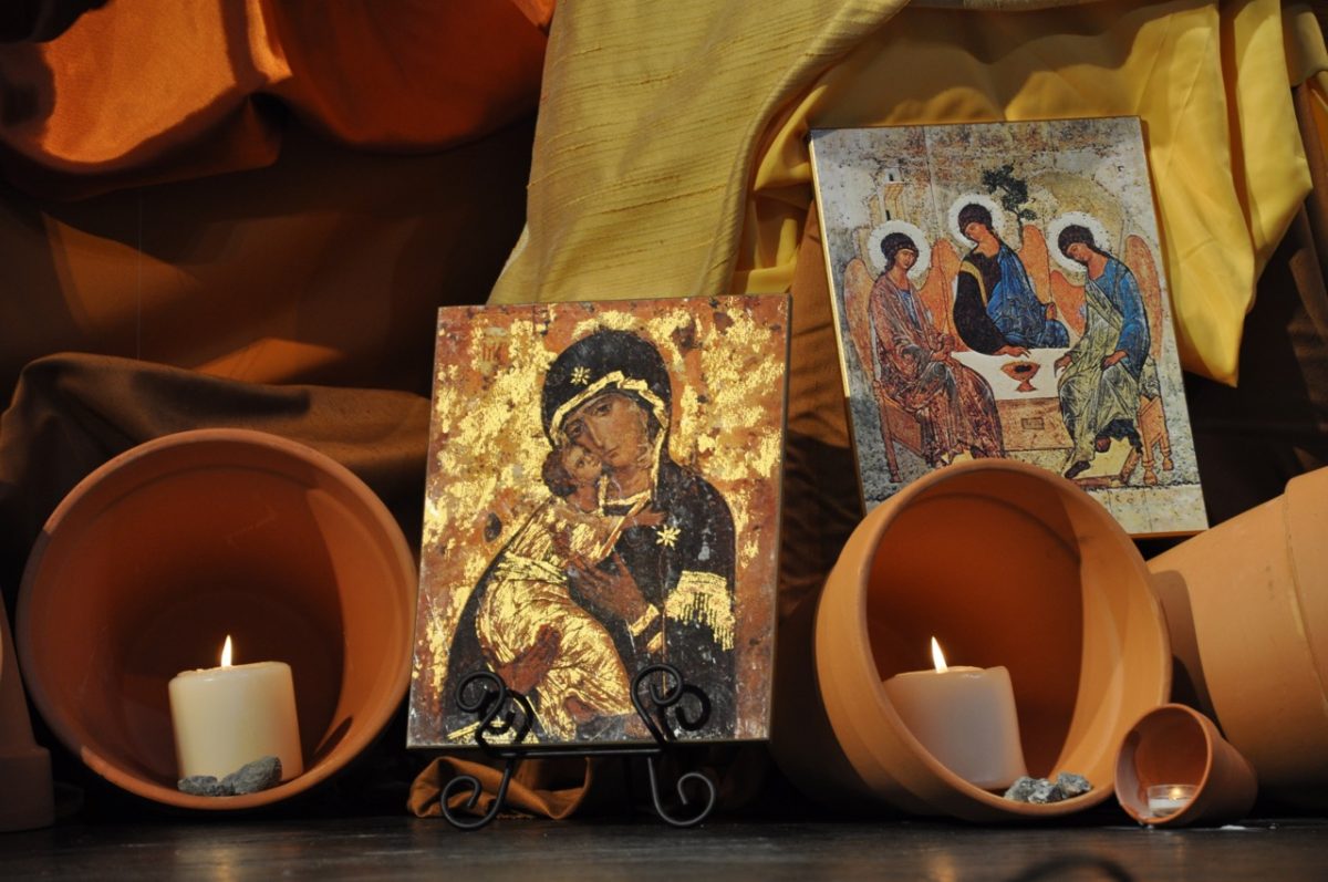 Small paintings with two candles against a background of layered cloth.